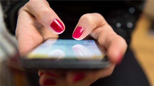 Eine Frau tippt auf einem Smartphone.