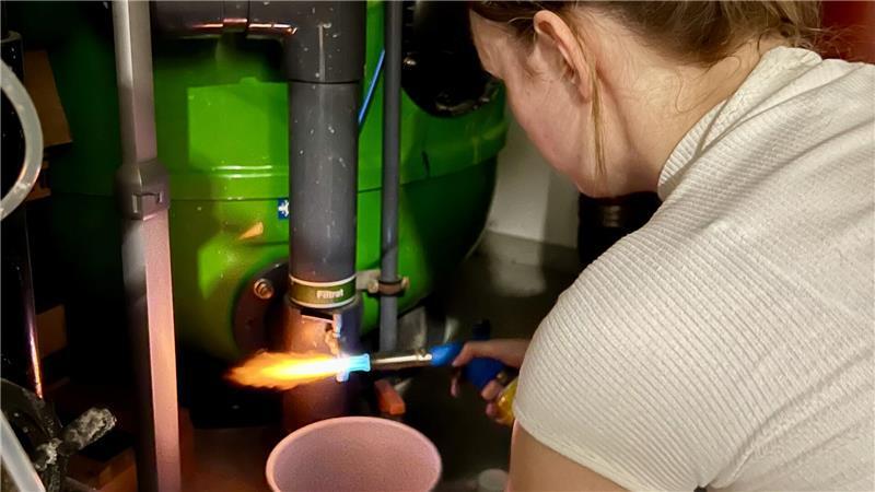 Bevor die Hygienekontrolleurin Kerstin Rinne eine Wasserprobe der Schwimmbadtechnik nimmt, erhitzt sie den Wasserhahn zur Desinfektion.