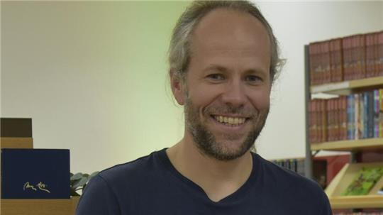 Porträt von Peter Jobmann mit Bücherregalen im Hintergrund