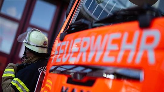 Ein Feuerwehrmann steht neben einem Einsatzfahrzeug.