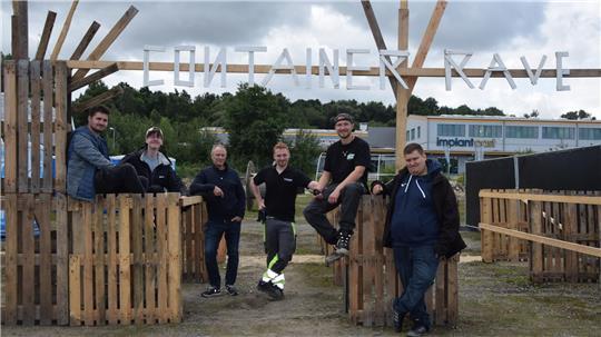 Bis zu 30 ehrenamtliche Helfer aus Buxtehude und Umgebung sind am Aufbau des Veranstaltungsgeländes für den Container Rave am Alten Postweg in Buxtehude beteiligt. Das Foto zeigt einige von ihnen am Eingangstor.