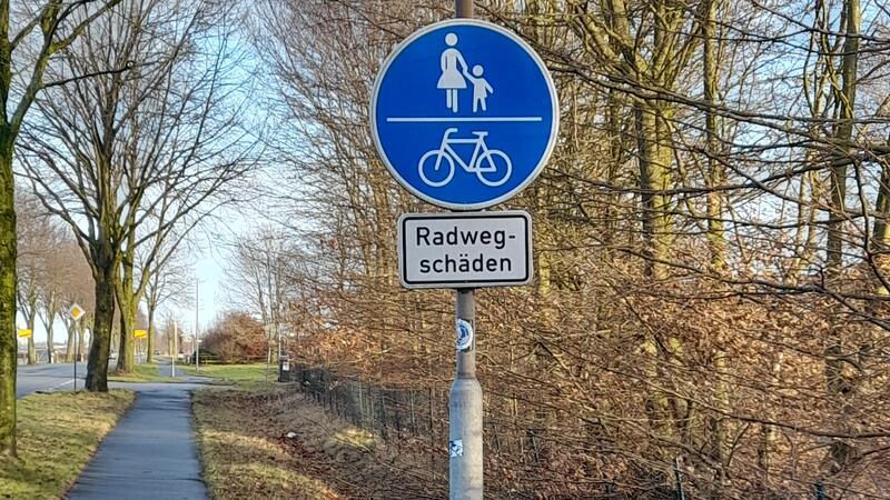 Bisherige Maßnahme: Ein Schild weist auf die Schäden am Radweg hin.
