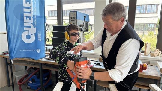 Björn Quelle, Geschäftsführer von Quelle Holzbau aus Bargstedt, zeigt Elias den Umgang mit dem Druckluftnagler.