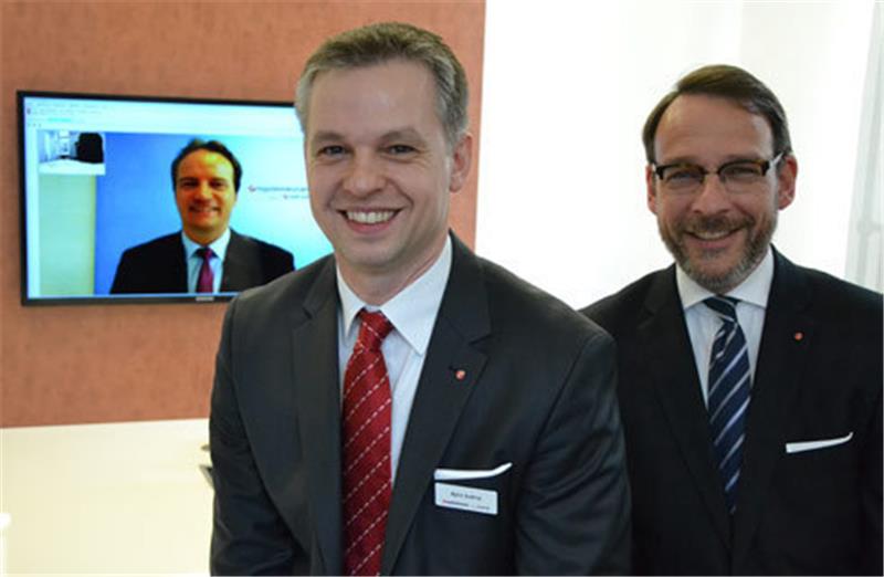 Björn Suttrop, Leiter des Filialverbundes Buxtehude/ Stade (Mitte) und Tim Ockert, Niederlassungsleiter der Privatkunden Bank der HVB Niederlassung Hamburg/Land Niedersachsen (rechts).  Auf dem Bildschirm ist Claus Floegel, Filialleiter der Online Filiale, live per Webcam zugeschaltet. Foto Schunk