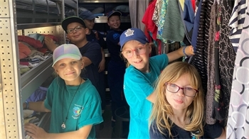 Blaulichttag 2026 Kinder vom Jugendrotkreuz Lühe und Horneburg sowie der Jugendfeuerwehr Assel schauen sich in der mobilen Kleiderkammer des DRK um.