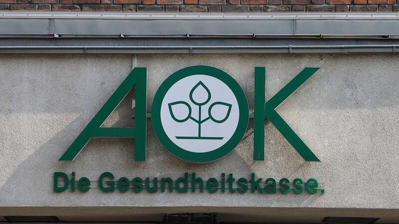 Blick auf das Logo der Krankenkasse AOK an einem Gebäude.