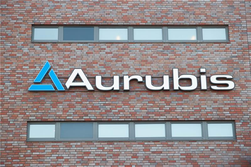 Blick auf das Logo und den Schriftzug „Aurubis“ am Firmengebäude. Der MDax-Konzern will jetzt seine Investitionen aufstocken. Ein entsprechendes Paket von rund 530 Millionen Euro wurde vom Aufsichtsrat genehmigt. Foto: Georg Wendt/dpa
