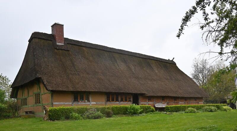 Blick auf das Niederdeutsche Hallenhaus auf dem Gelände des Bäuerlichen Hauswesens, hinter dem Gebäude wird das neue Baugebiet ab 2025 erschlossen.