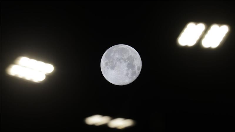 Blick auf den Mond zwischen Straßenlaternen in Riedlingen. 