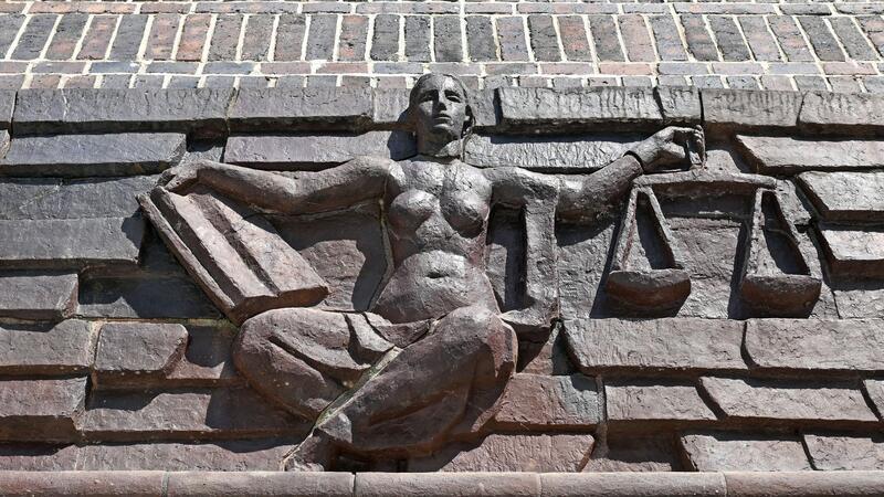 Millionenbetrug: Verteidigung fordert Haftstrafen Blick auf die Justitia über dem Eingang eines Landgerichts.