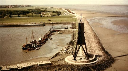 Blick auf die Kugelbake mit Bauhafen, wie er sich in den 1950er und 1960er Jahren darbot. Es gab hier einen beachtlich langen Anlegesteg. Im Hintergrund ist vor dem Fort Kugelbake noch die alte Strandhalle zu erkennen.