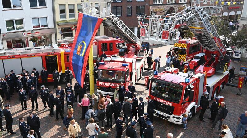 Blick auf die alte (mit Fahne) und die neue Drehleiter (rechts) der Ortsfeuerwehr Buxtehude vor der Taufe auf dem Rathausplatz.