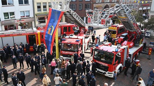 Blick auf die alte (mit Fahne) und die neue Drehleiter (rechts) der Ortsfeuerwehr Buxtehude vor der Taufe auf dem Rathausplatz.