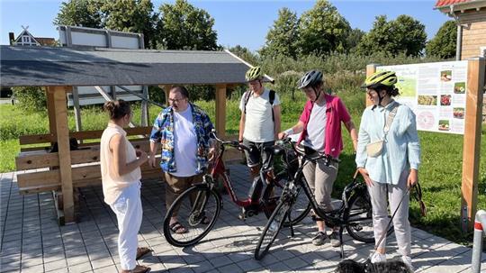 Blick auf die neue Schutzhütte für Fahrradfahrer in Mittelnkirchen. Joachim Streckwaldt (CDU, Zweiter von links) im Gespräch mit Regionalmanagerin Anne Rosenfeld (links) und Urlaubsgästen aus NRW.