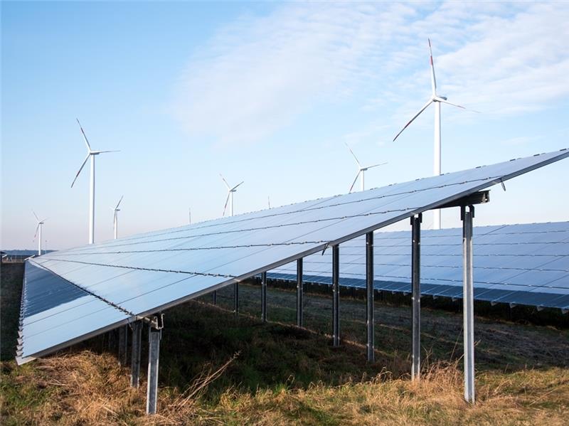 Blick auf einen Solarpark: Im Hintergrund sind Windräder zu sehen. Foto: Daniel Bockwoldt/dpa