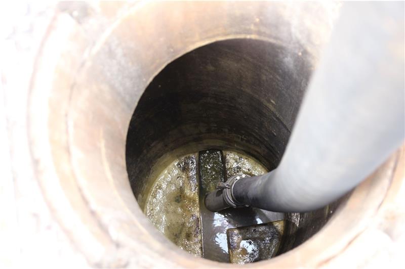 Blick in den Kanalschacht an der Altländer Straße, in dem der Saugschlauch hängt.