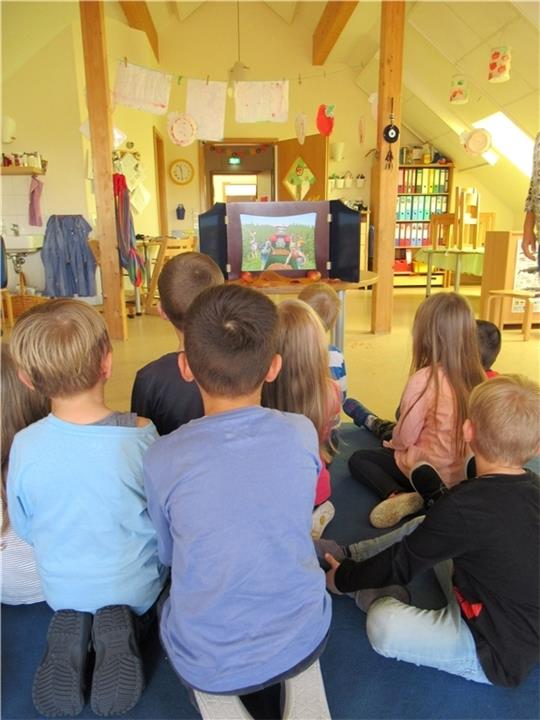 Blick in die Kita Hand in Hand in Jork, einer von 14 Sprach-Kitas im Kreis Stade: Kinder sitzen im Bilderbuchtheater. Hinter dem Holzrahmen (japanisch: Kamishibai) sitzt jemand, der die Bilder wechselt und dazu vorliest.