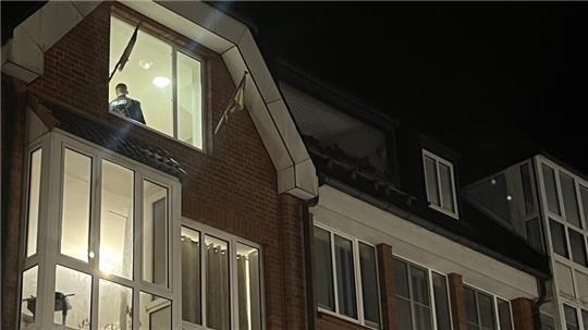 Blick von der Fußgängerzone auf die durchsuchten Wohnungen während der Razzia in der Buxtehuder Altstadt. Mit dem Rücken zum Fenster sichert ein Polizist ein Zimmer.