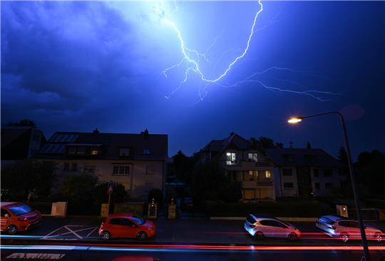 Blitze entladen sich am Abendhimmel während eines schweren Gewitters über den Häusern im Stadtteil Sachsenhausen . Foto: Arne Dedert/dpa