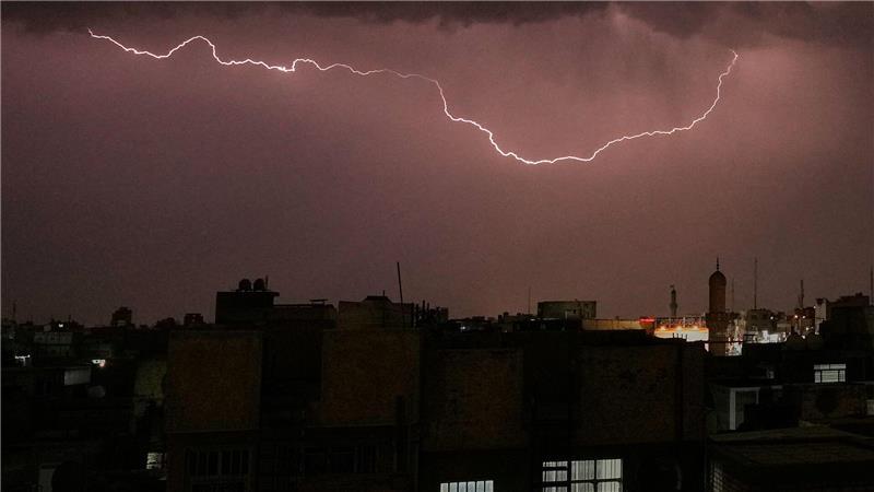 Blitze erhellen den Himmel, während ein Gewitter über Bagdad hinwegzieht.