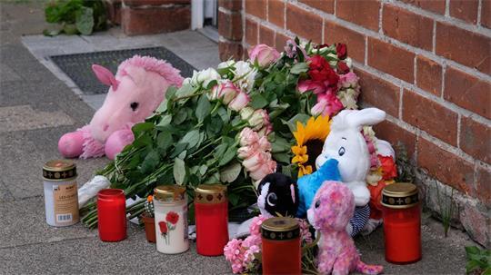 Blumen, Kerzen und Plüschtiere vor dem Wohnhaus.