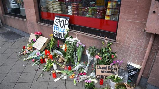 Blumen, Kerzen und Schilder liegen in Mannheim an dem Ort, an dem ein Mann Anfang Mai 2022 nach einer Polizeikontrolle starb.
