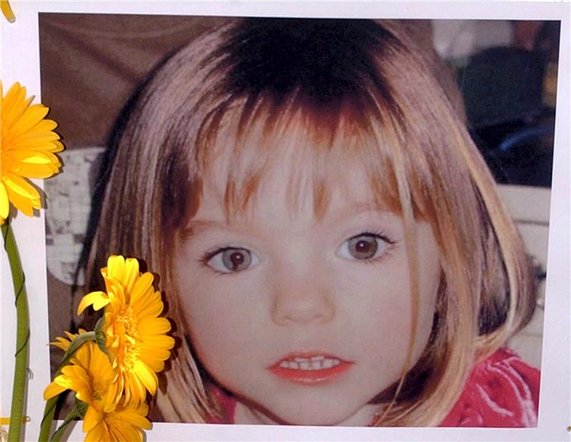 Verdächtiger im Fall Maddie beschwert sich über Haftbedingungen Blumen stehen vor einem Bild, das die verschwundenen Madeleine McCann (Maddie) auf einem Foto zeigt, das ihre Eltern im Zusammenhang mit dem Verschwinden des Kindes veröffentlich haben. Foto: Luis Forra/LUSA FILE/dpa