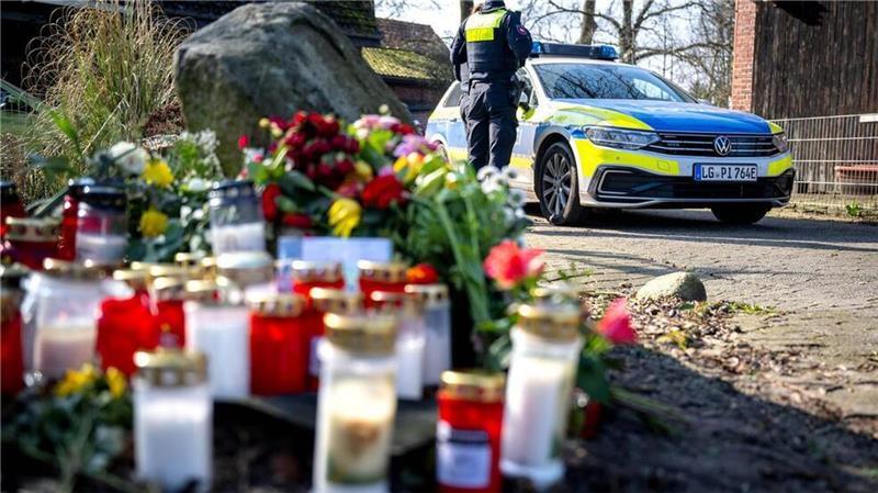 Blumen und Kerzen liegen nach der Tatnacht vor einem Einfamilienhaus.