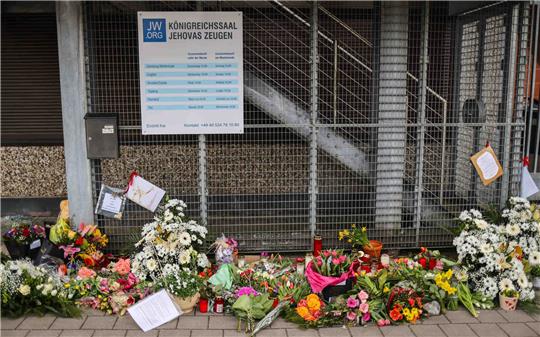 Blumen und Kerzen sind vor dem Eingangsbereich eines Gemeindehauses der Zeugen Jehovas zu sehen. Foto: Christian Charisius/dpa