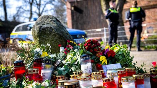 Blumen und Kerzen vor einem Einfamilienhaus.