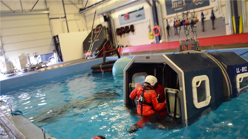 Vom Überleben auf rauer See: So hart ist das Offshore-Training in Bremerhaven Boarding: Der angehende Servicetechniker für Offshore-Windkraftanlagen André Ullert klettert bei einem Überlebenstraining in Bremerhaven auf seinen Platz hinten rechts im Hubschrauber-Simulator. Das Fenster neben sich kann Ullert herausdrücken. Die Öffnung bildet wie bei einem echten Hubschrauber den Notausgang. Käme er während der Übung nicht hindurch, könnte er auch durch die offene Rückwand auftauchen - diese Möglichkeit gäbe es im Ernstfall aber nicht.Foto: Saure