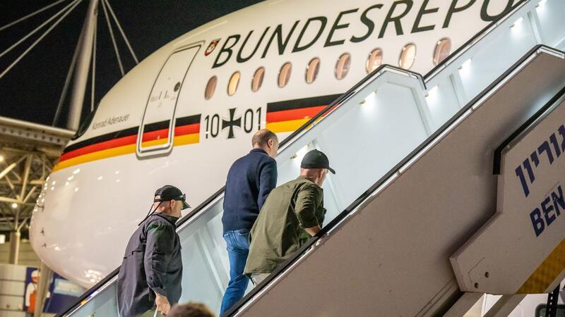 Bodyguards bringen Bundeskanzler Olaf Scholz nach dem Luftalarm in den Regierungs-Airbus.