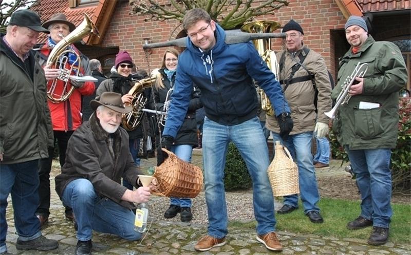Brauchtum in Nottensdorf : Eierschnorrer Hans Osterholz trägt die „Drach“, die Traditions-Trage mit den beiden Korn-Korbflaschen, Hans-Hinrich Bockelmann füllt den Schnaps um. Die Blaskappelle bedankt sich mit einem Ständchen für Eier und S