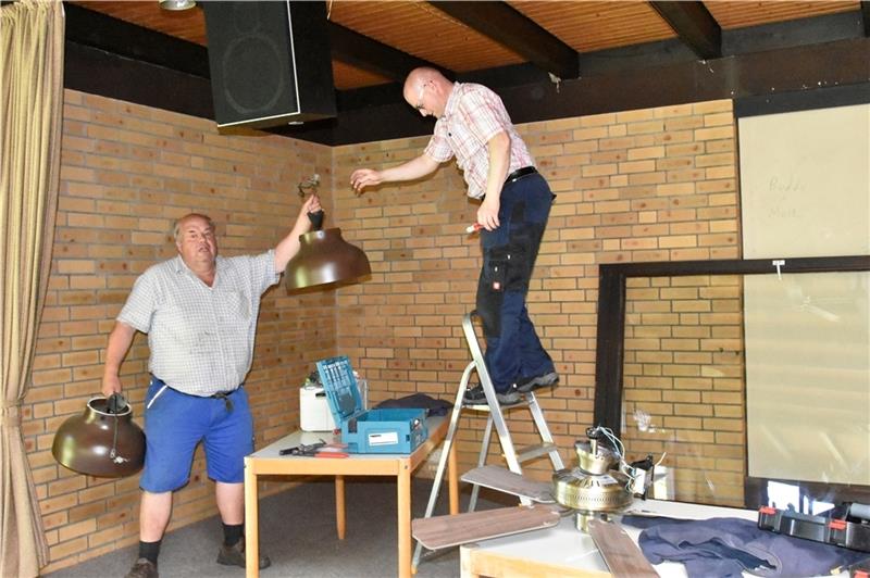 Brests Bürgermeister Johann Höft (links) hilft dem Elektriker Wilfried Tomforde beim Abbau der Lampen im Dorfgemeinschaftshaus. Fotos: Felsch
