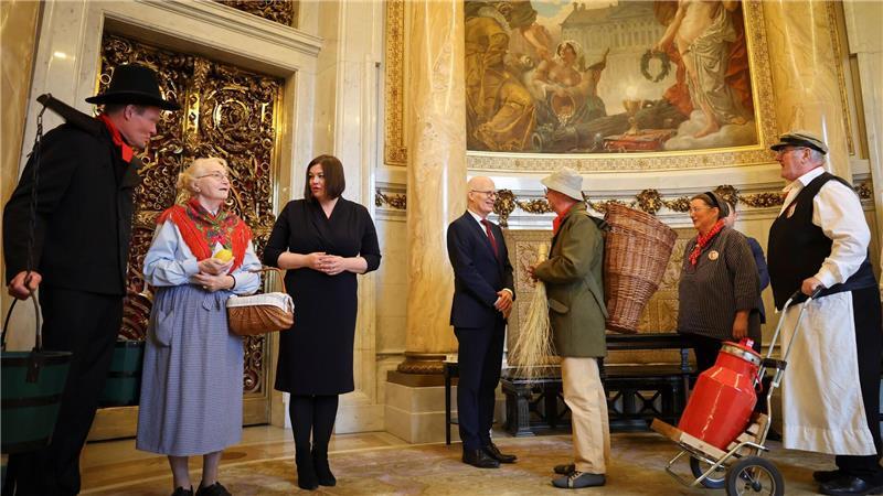 Bürgerinnen und Bürger, gekleidet in historischen Kostümen, besuchen das Rathaus. 