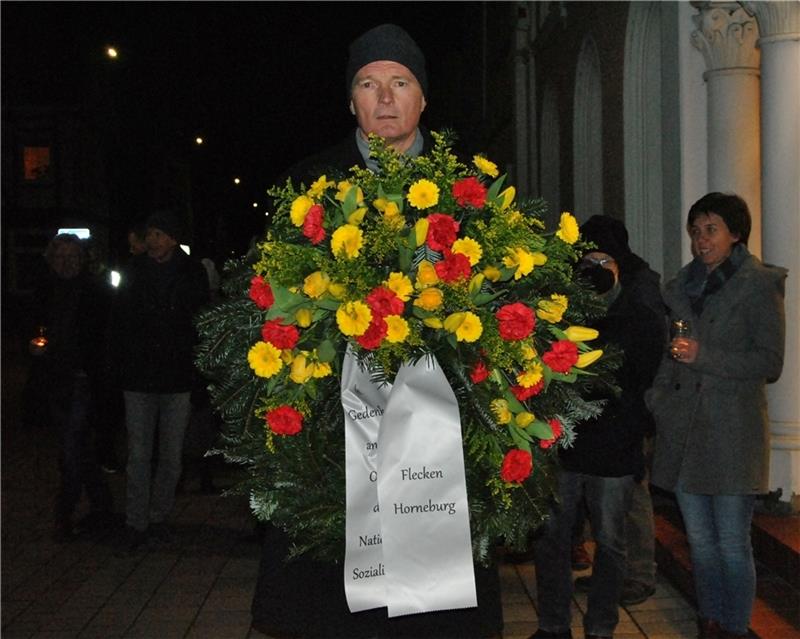 Bürgermeister Jörk Philippsen geht mit einem Kranz voraus - vom Rathaus über den Auedamm zum Gedenkstein. Foto: Lohmann