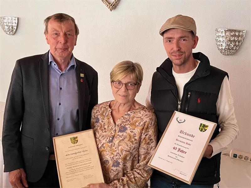 Marktbummel an der Oldendorfer Kirche: Urkunden und ein Lebkuchenherz Bürgermeister Johann Schlichtmann gratuliert Wirtin Heimtraut Judel vom Landgasthof Heins zum 25-jährigen Betriebsjubiläum und dankt David Bode vom gleichnamigen Schaustellerbetrieb für 40 Jahre Mitgestaltung des Herbstmarkts Oldendorf.