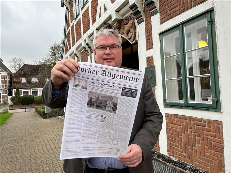 Bürgermeister Matthias Riel hält die Zeitung mit dem Neujahrsgruß der Gemeinde Jork vor dem Rathaus in seinen Händen. Foto: Vasel