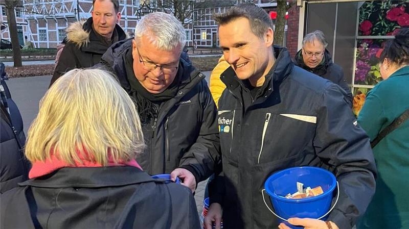Bürgermeister Matthias Riel und Udo Feindt beim Glücksschweinchen-Verkauf in Jork.