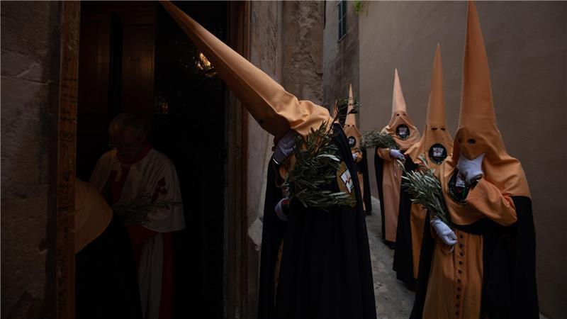 Büßer ziehen bei der Palmsonntagsprozession in der Innenstadt von Palma auf Mallorca zur Kirche.