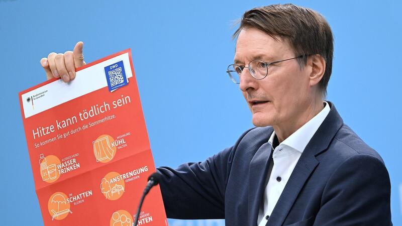 Mehr Vorbeugung gegen Hitzetote im Sommer Bundesgesundheitsminister Karl Lauterbach (SPD) hält ein Plakat zum Thema Hitzeschutz hoch.