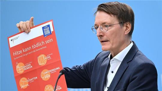 Bundesgesundheitsminister Karl Lauterbach (SPD) hält ein Plakat zum Thema Hitzeschutz hoch.