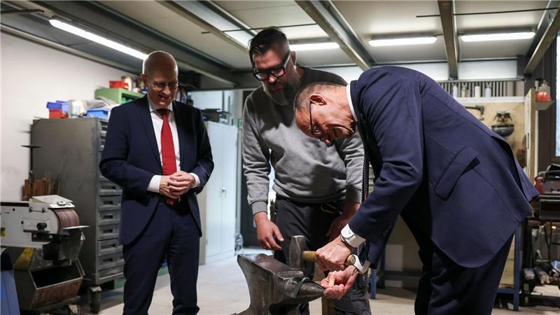 Bundeskanzler Friedrich Merz greift in einer Hamburger Schlosserei zum Hammer.