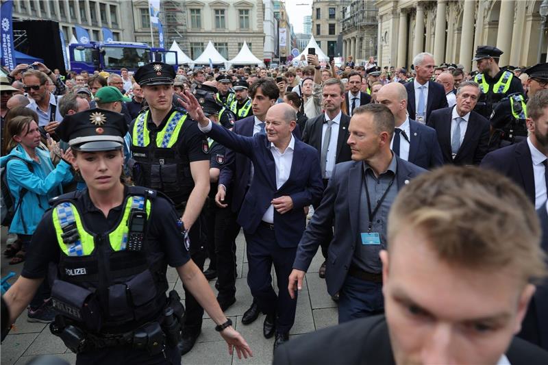 Polit-Prominenz, viel Wind und ein sexy Auftritt bei Einheitsfeier in Hamburg Bundeskanzler Olaf Scholz (M) winkt auf seinem Weg vom Bürgergespräch in der Handelskammer.