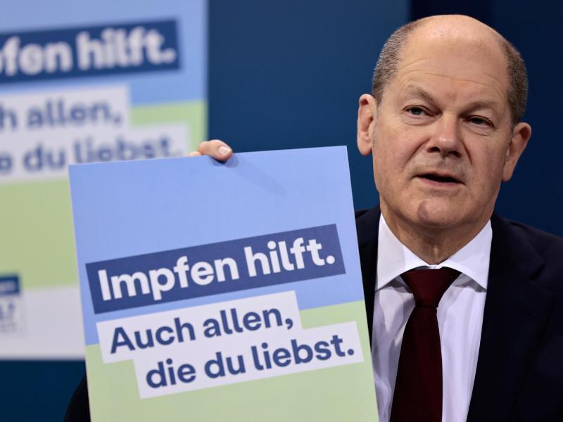 Bundeskanzler Olaf Scholz (SPD) präsentiert ein Plakat für eine neue Impfkampagne. Foto: Hannibal Hanschke/POOL AP/dpa