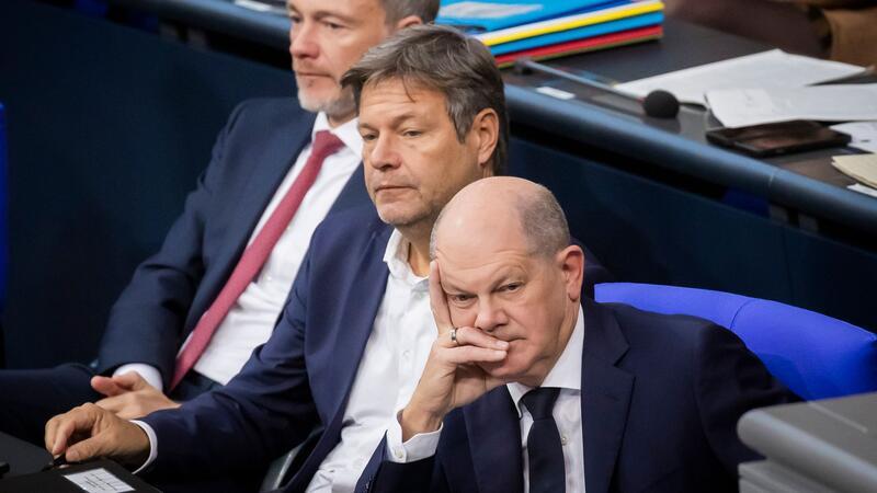 Bundeskanzler Olaf Scholz (SPD, r-l), Wirtschaftsminister Robert Habeck (Bündnis 90/Die Grünen) und Finanzminister Christian Lindner (FDP) verfolgen im Deutschen Bundestag die Debatte.