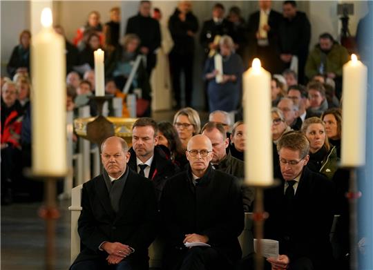 Bundeskanzler Olaf Scholz (erste Reihe, l-r, SPD) und Peter Tschentscher (SPD), Erster Bürgermeister von Hamburg und Daniel Günther (CDU), Ministerpräsident von Schleswig-Holstein, nehmen am Trauergottesdienst für die Opfer der Messerattacke in einem Regionalzug von Kiel nach Hamburg teil.  Foto: Marcus Brandt/dpa-Pool/dpa