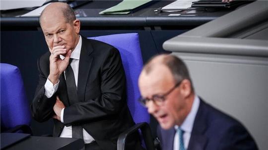 Bundeskanzler Olaf Scholz (l) hört einer Rede von CDU-Chef Friedrich Merz im Bundestag zu.