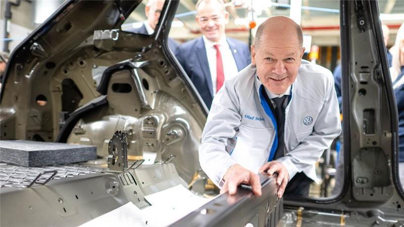 Bundeskanzler Olaf Scholz legt im VW-Werk Emden eine Dämmmatte in einen Wagen.