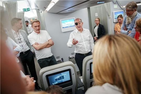 Bundeskanzler Olaf Scholz (r, SPD) und Finanzminister Christian Lindner (FDP) sprechen auf dem Flug nach Neu Dehli mit Journalisten.